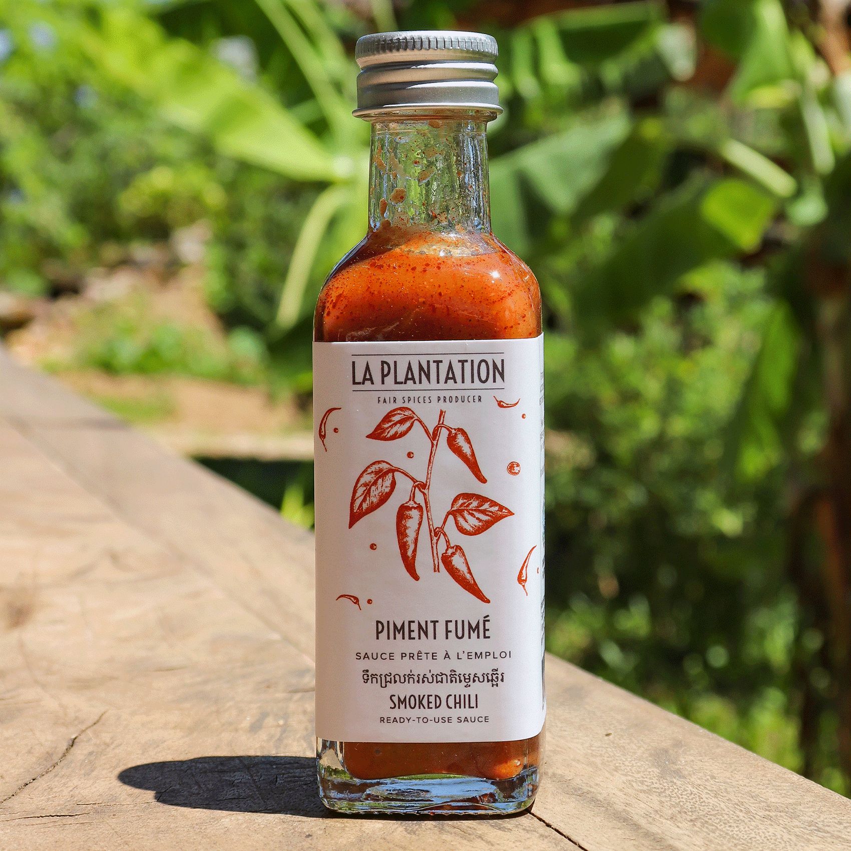 bouteille de sauce au piment fumé dans un décor tropical