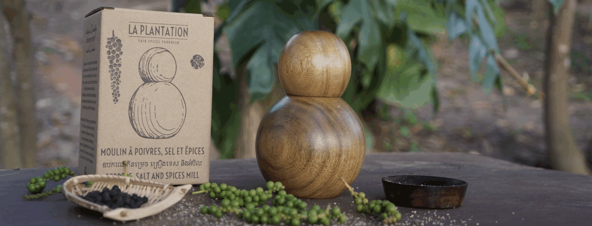 Pfeffermühle mit kugelförmigen Pfefferkörnern und einer Packung Kampot-Pfeffer