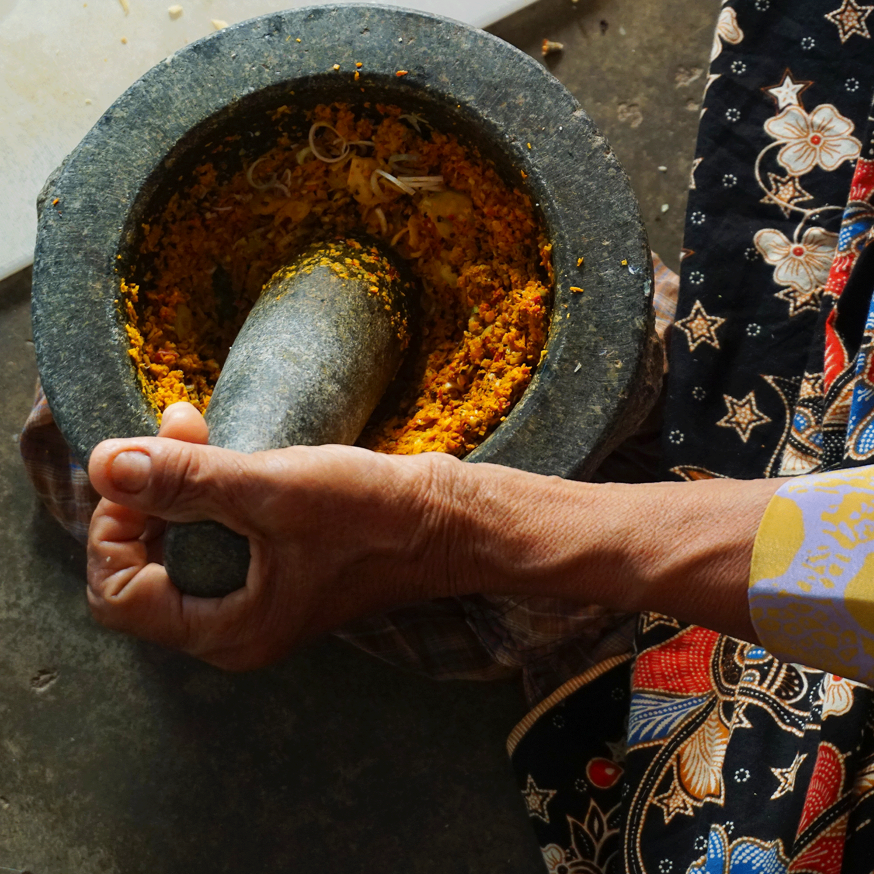 hand using a mortar to smash curry powder