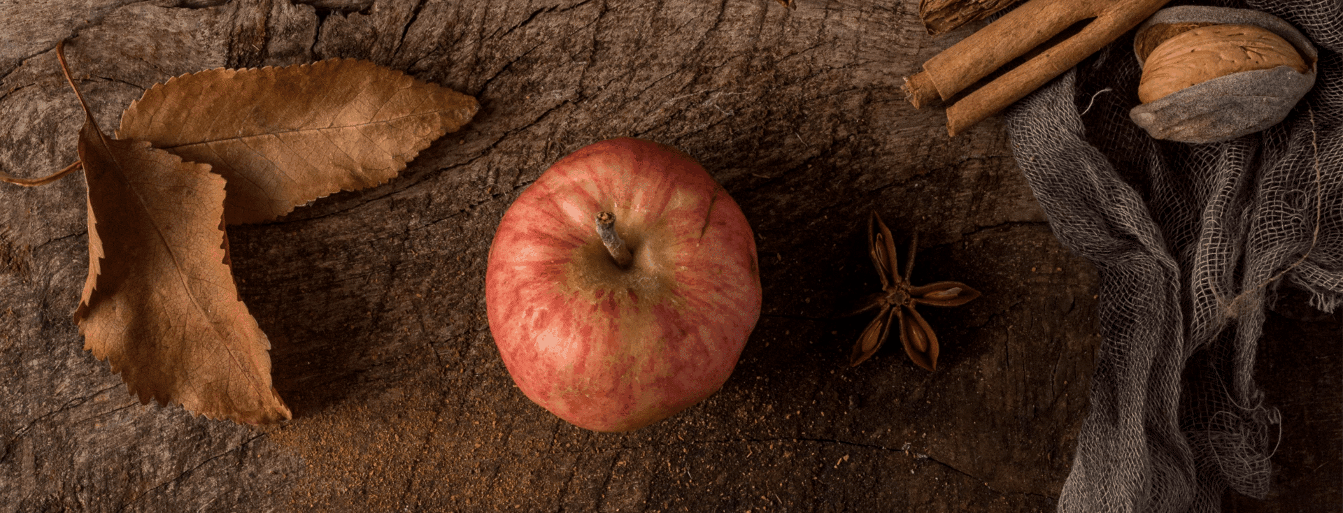 apple and a cinnamon stick on a wooden surface
